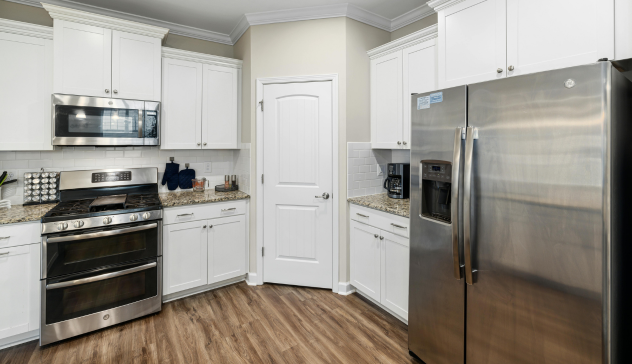 A modern small kitchen with sleek white cabinets and durable granite countertops, perfect for busy households. The spacious layout and neutral tones create a functional and inviting cooking space. The high-quality materials are not only visually appealing but also designed to withstand heavy use, making them an ideal choice for home chefs or families who love to cook. The bright, airy atmosphere enhances the feeling of openness in the kitchen.