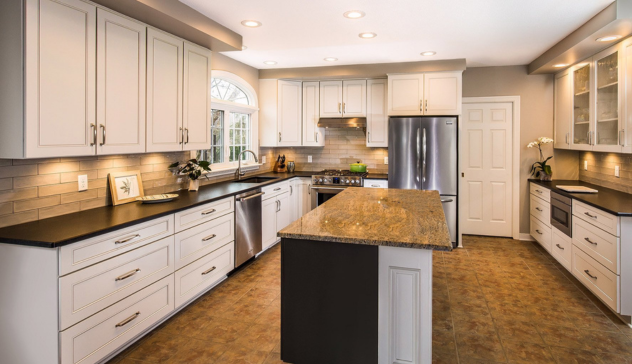 A spacious kitchen featuring ambient recessed lighting, task lighting under cabinets, and accent lights to enhance visibility and style.